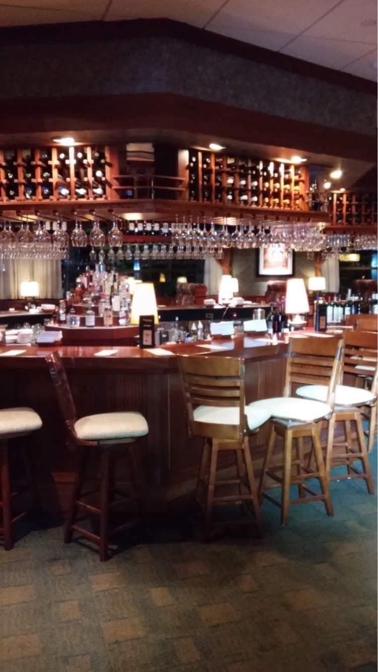 Restaurant bar with warm lamps, lit wine shelving and overhead accent lighting
